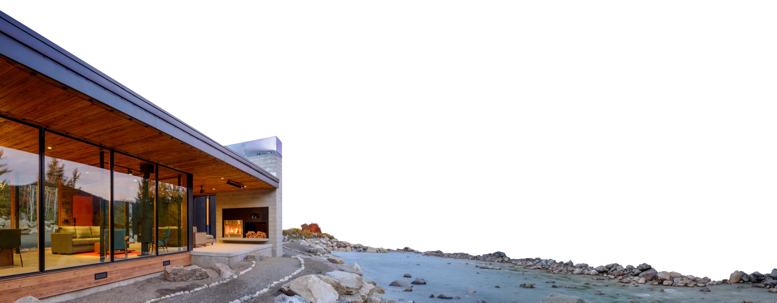 Modern home featuring premium window and door services, with large glass walls and an outdoor fireplace overlooking a rocky shoreline.