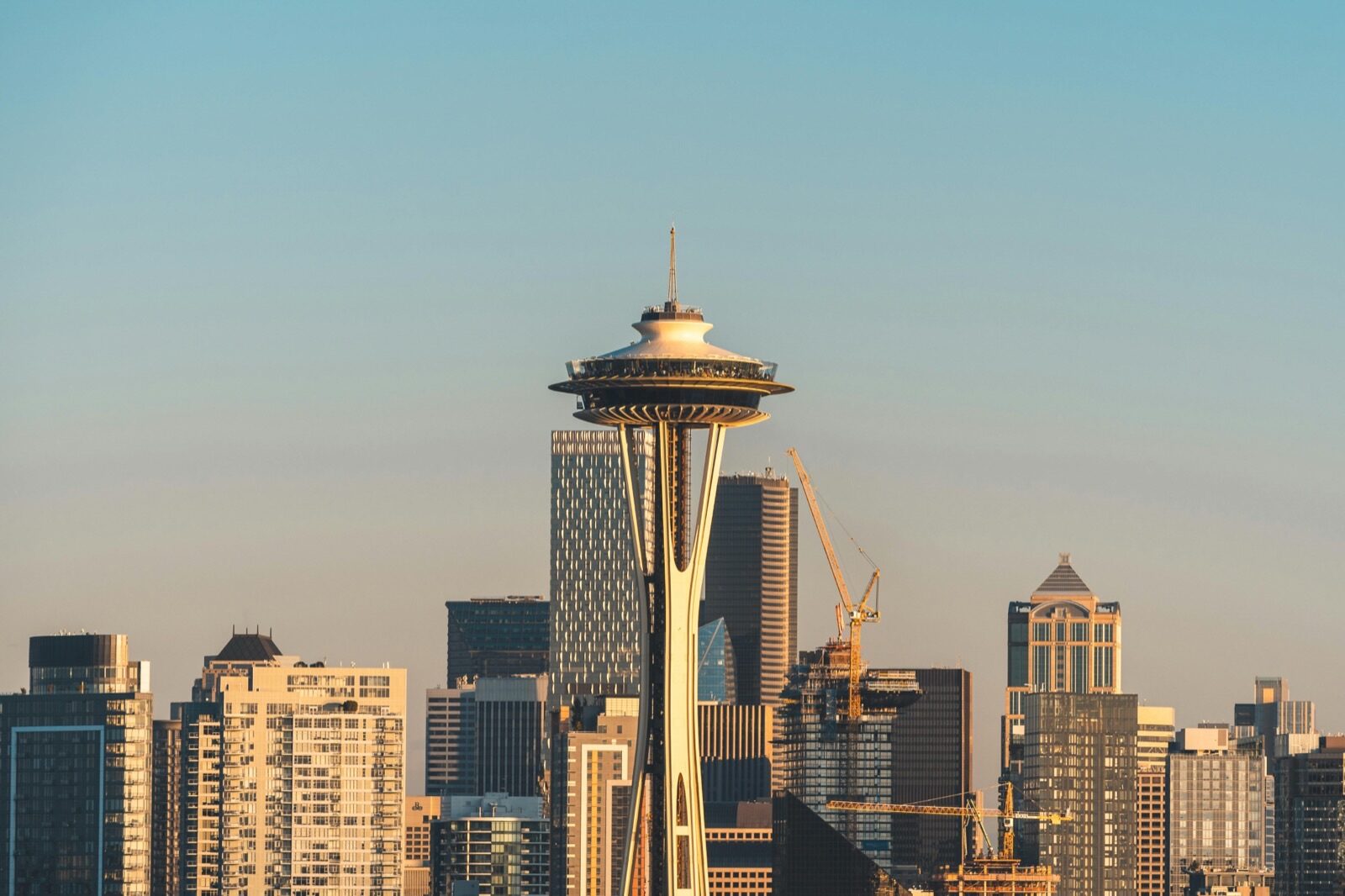 The Space Needle tower stands in front of the Seattle skyline, viewed through the windows and doors of the city.